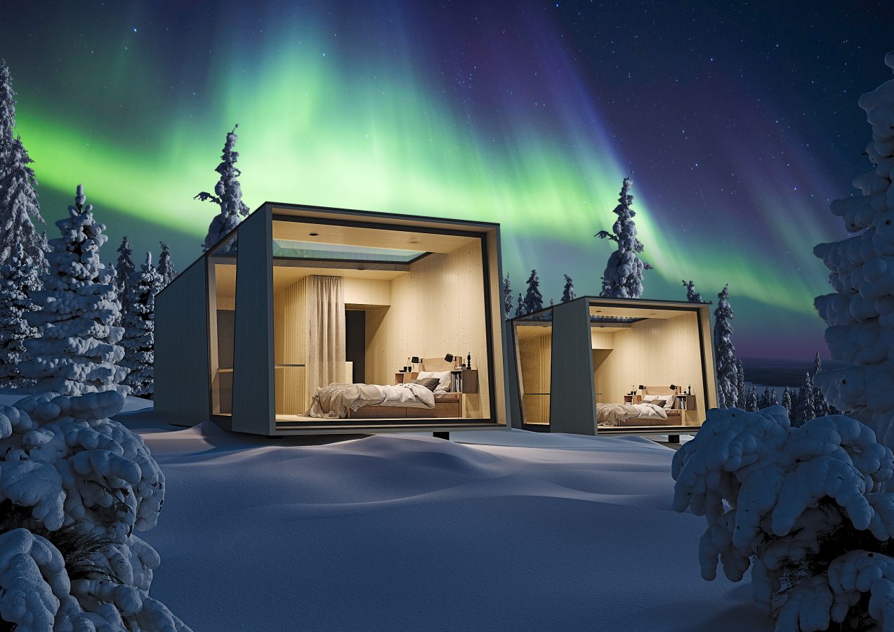Vuolas housing in snowy forest with northern lights.