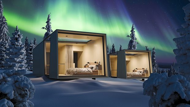 Vuolas housing in snowy forest with northern lights.